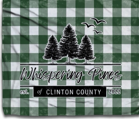 Green and white buffalo plaid blanket with the Whispering Pines of Clinton County three-pines logo